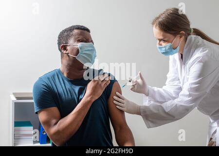 Vaccination pendant une pandémie de covid, jeune infirmière effectuant une injection. Banque D'Images
