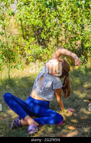 Défocus préadolescence caucasienne pratiquant le yoga dans le parc, la forêt, à l'extérieur, à l'extérieur. Méditation, concentration. Style de vie bien-être. Portrait de la jeune fille de yoga Banque D'Images