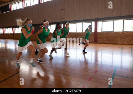 Une équipe de basket-ball féminine diversifiée portant un masque facial et s'exécutant Banque D'Images