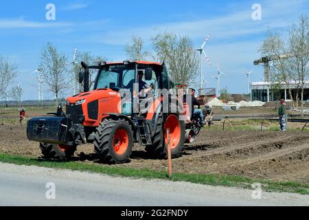 Podersdorf, Autriche - 04 mai 2021: Des helpers inconnus sur un tracteur plantant mécaniquement des vignes Banque D'Images