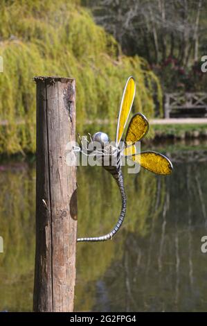 Sculpture de libellule en métal jaune sur un poteau près du lac Magnolia au Himalayan Garden & Sculpture Park, Grewelthorpe, Ripon, North Yorkshire. ROYAUME-UNI. Banque D'Images