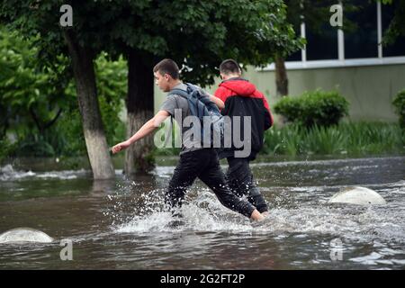 Non exclusif: SIEVIERODONETSK, UKRAINE - 10 JUIN 2021 - les garçons se sont empais dans l'eau de pluie dans une rue inondée après une douche à Sievierodonetsk, Luhansk Banque D'Images