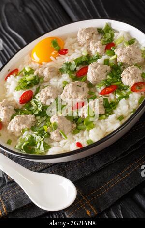 Authentique soupe de riz Khao tom moo Thai avec porc haché dans l'assiette sur la table. Verticale Banque D'Images