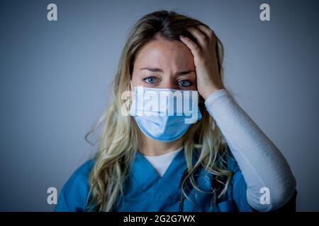 Portrait d'un médecin ou d'une infirmière triste et submergé portant un masque facial protecteur, qui a l'air épuisé déprimé et inquiet en raison de l'épidémie de coronavirus. EMO Banque D'Images