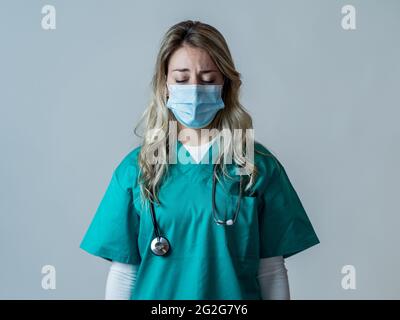 Portrait d'un médecin ou d'une infirmière triste et submergé portant un masque facial protecteur, qui a l'air épuisé déprimé et inquiet en raison de l'épidémie de coronavirus. EMO Banque D'Images