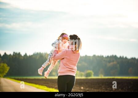 Mère et enfant marchant sur la route de campagne entre les champs agricoles vers le vilage de la forêt. Banque D'Images