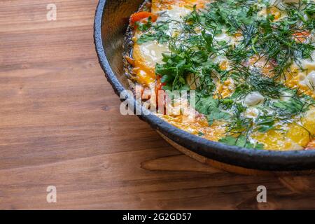 Œufs pochés aux tomates et aux épices appelés « shakshuka », cuits dans une casserole en fonte, sur une table en bois. Style rustique. Vue de dessus. Banque D'Images