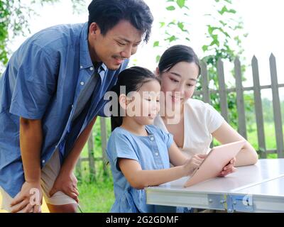 La famille heureuse de trois utilise une tablette informatique en extérieur photo de haute qualité Banque D'Images