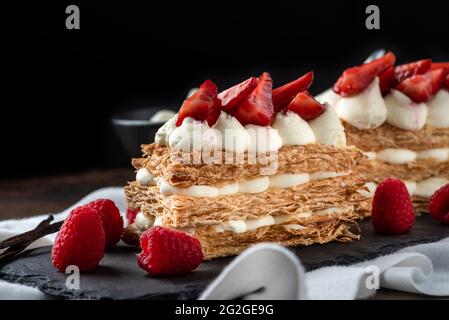 Fraises, framboises et crème mille feuille sur assiette en pierre noire Banque D'Images