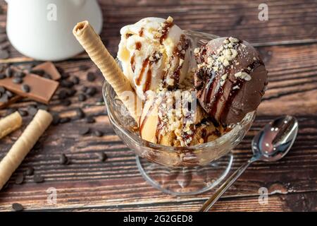 Glace Roma au chocolat, à la crème et au caramel dans un bol en verre avec une sauce au chocolat et aux noisettes. Banque D'Images