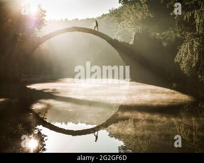 Lever de soleil derrière le Rakotzbrücke historique dans le parc Kromlau Rhododendron. Banque D'Images