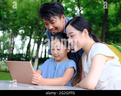 La famille heureuse de trois utilise une tablette informatique en extérieur photo de haute qualité Banque D'Images