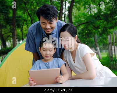 La famille heureuse de trois utilise une tablette informatique en extérieur photo de haute qualité Banque D'Images