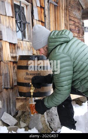 Jeune homme versant de la bière, baril de bière, brasserie Mittenwald, cabane de montagne, hiver, atmosphérique Banque D'Images