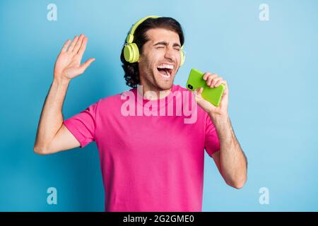 Portrait de gentil gai gars tenant dans les mains gadget chant simple ayant amusant isolé sur fond bleu clair de couleur Banque D'Images