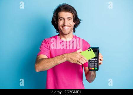 Portrait d'un sympathique gars gai tenant le terminal de gadgets à l'aide de la carte virtuelle d'application d'achat sans fil nfc isolée sur la couleur bleu vif Banque D'Images