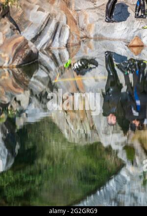 Suisse, Tessin, Vallée de la Verzasca, Verzasca, plongeurs dans la rivière au bassin populaire avec les roches de granit: Réflexion dans l'eau. Banque D'Images