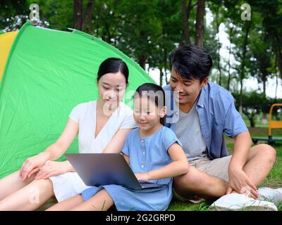 Une famille heureuse de trois personnes utilise un ordinateur pour surfer sur Internet en plein air de haute qualité photo Banque D'Images