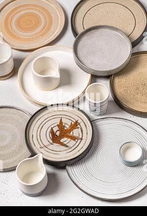 Belle vaisselle faite à la main, assiettes en céramique artisanales vides et tasses avec feuille d'érable sur fond clair. Banque D'Images
