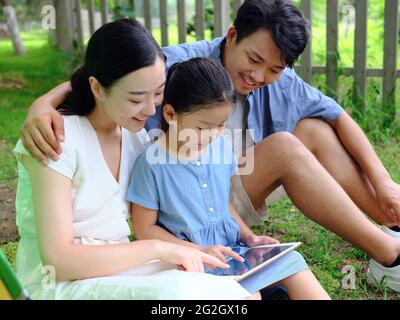 La famille heureuse de trois utilise une tablette informatique en extérieur photo de haute qualité Banque D'Images