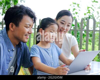 Une famille heureuse de trois personnes utilise un ordinateur pour surfer sur Internet en plein air de haute qualité photo Banque D'Images