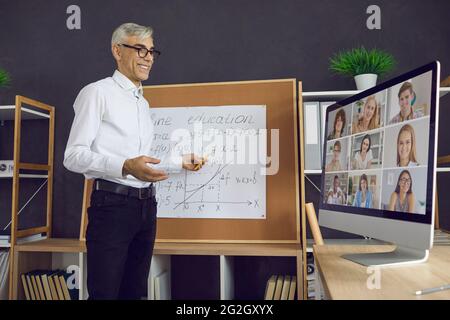Enseignant debout devant un conseil et donnant une leçon en ligne à un groupe d'élèves Banque D'Images