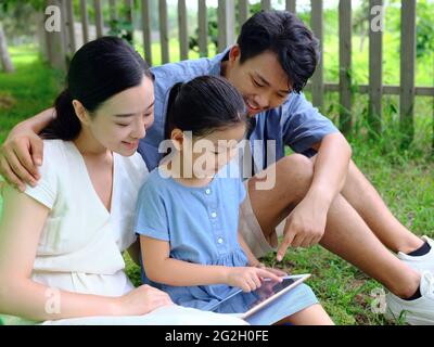 La famille heureuse de trois utilise une tablette informatique en extérieur photo de haute qualité Banque D'Images