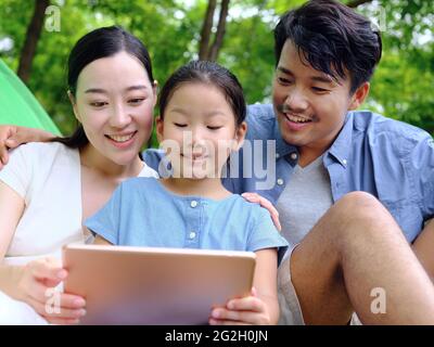 La famille heureuse de trois utilise une tablette informatique en extérieur photo de haute qualité Banque D'Images