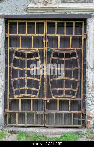 Ancienne porte avec une porte barrée en métal rouillé en forme de fûts de vin. Cadenassé et abandonné. Banque D'Images