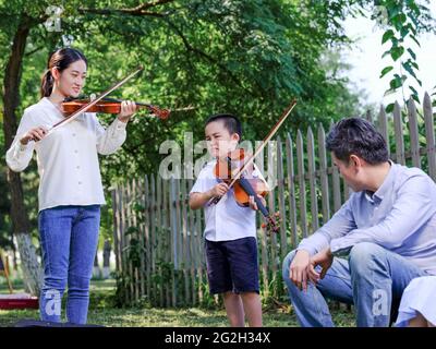 Bonne famille de trois personnes jouant du violon dans le parc photo de haute qualité Banque D'Images