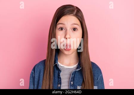 Photo portrait de la petite fille grimace montrant la langue duper isolé sur fond rose pastel Banque D'Images