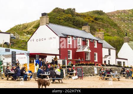 PORTHDINLLAEN, PAYS DE GALLES – MAI 9 2021 : personnes durant la pandémie Covid-19 en dehors de l'auberge Tŷ Coch à Porthdinllaen, Gwynedd, pays de Galles, paysage. Banque D'Images