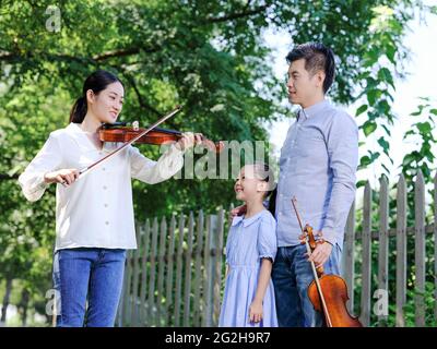 Bonne famille de trois personnes jouant du violon dans le parc photo de haute qualité Banque D'Images