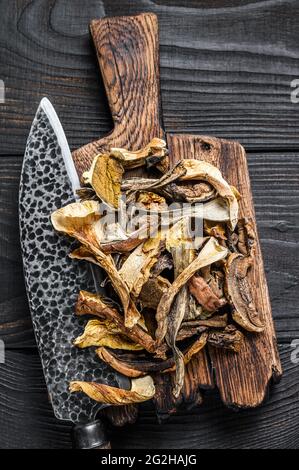 Champignons sauvages séchés Porcini tranchés sur une planche à découper en bois. Arrière-plan en bois noir. Vue de dessus Banque D'Images