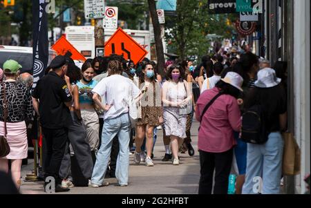 Toronto, Canada. 11 juin 2021. Les gens marchent dans une rue à Toronto, Ontario, Canada, le 11 juin 2021. L'Ontario est entré dans la première étape de son plan de réouverture vendredi, les magasins et les restaurants faisant du thé avec les clients alors que la province a levé certaines de ses restrictions COVID-19 pour la première fois depuis des mois. Credit: Zou Zheng/Xinhua/Alamy Live News Banque D'Images