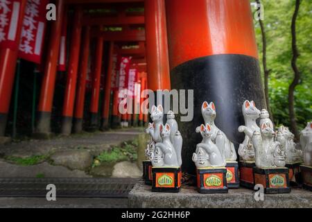 De minuscules statues de renards à la base de cette porte de torii à l'entrée de ce sanctuaire à Kamakura, Japon. Banque D'Images