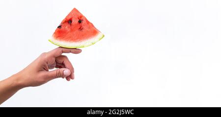 Pièce de pastèque rouge dans la main femelle. Concept été créatif. Composition minimale de fruits d'été sur fond blanc. Banque D'Images