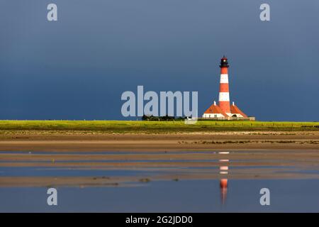 Phare de Westerheversand, ciel sombre, orage d'humeur, vue de la plage, reflet dans l'eau, péninsule d'Eiderstedt, Parc national de la mer des Wadden du Schleswig-Holstein, Allemagne, Schleswig-Holstein, côte de la mer du Nord Banque D'Images