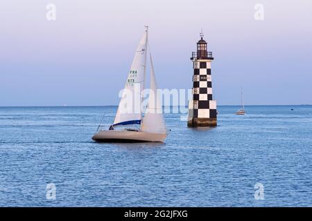 Un bateau à voile passe devant le phare la Perdrix, Île-Tudy près de Pont l’Abbé dans le sud du Finistère, ambiance nocturne, France, Bretagne, département du Finistère Banque D'Images