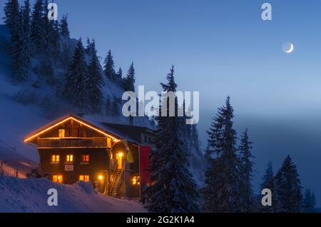 Cabane de montagne illuminée la nuit dans un paysage hivernal enneigé. Staufner House, Alpes Allgäu, Bavière, Allemagne, Europe Banque D'Images