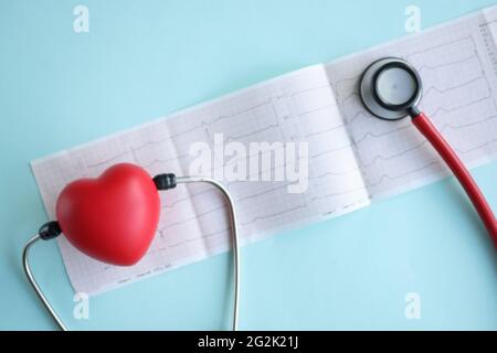 Stéthoscope et coeur rouge sur électrocardiogramme sur fond bleu gros plan Banque D'Images