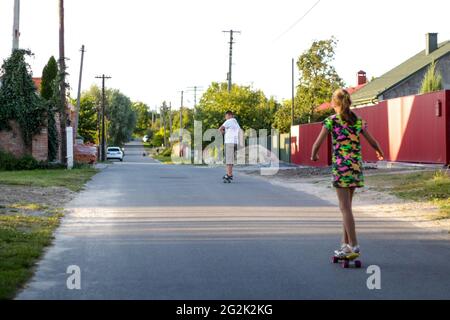 Redéfinit les enfants heureux jouant sur le skateboard dans la rue. Les enfants de race blanche à la planche de Penny, à la pratique du skateboard. Concept d'enfance et d'amitié Banque D'Images