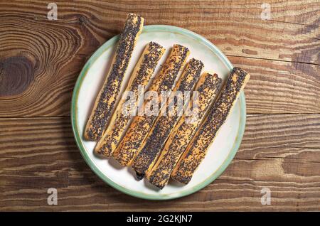 Biscuits avec graines de pavot dans l'assiette sur fond de bois, vue de dessus Banque D'Images