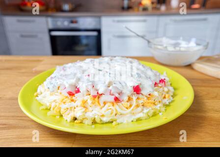 Le processus de fabrication d'une délicieuse salade de bâtonnets de crabe, de carottes, de fromage fumé et de sauce. Banque D'Images