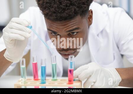 jeune homme scientifique utilisant une pipette automatique avec flacon en laboratoire médical Banque D'Images