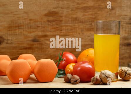 Haltères, jus d'orange, fruits et noix sur la table en bois, sport et santé concept de style de vie Banque D'Images