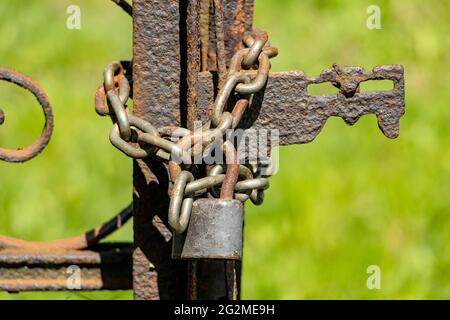 La porte rouillée est verrouillée par un cadenas avec une chaîne. Banque D'Images