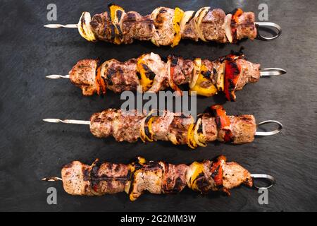 ed porc et agneau brochette ou Kebob avec poivron rouge et jaune et oignon sur une plaque d'ardoise foncée Banque D'Images