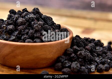 Baies d'Aronia bio dans un bol en bois Banque D'Images