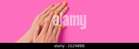 Des mains de femmes soignées avec un motif à ongles tendance sur fond rose Banque D'Images